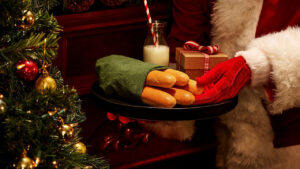 Santa holding a tray of breadsticks and a small gift