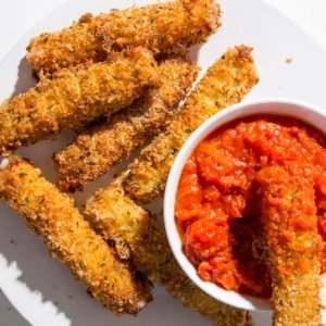 Crispy mozzarella sticks paired with tangy marinara sauce on a white plate.